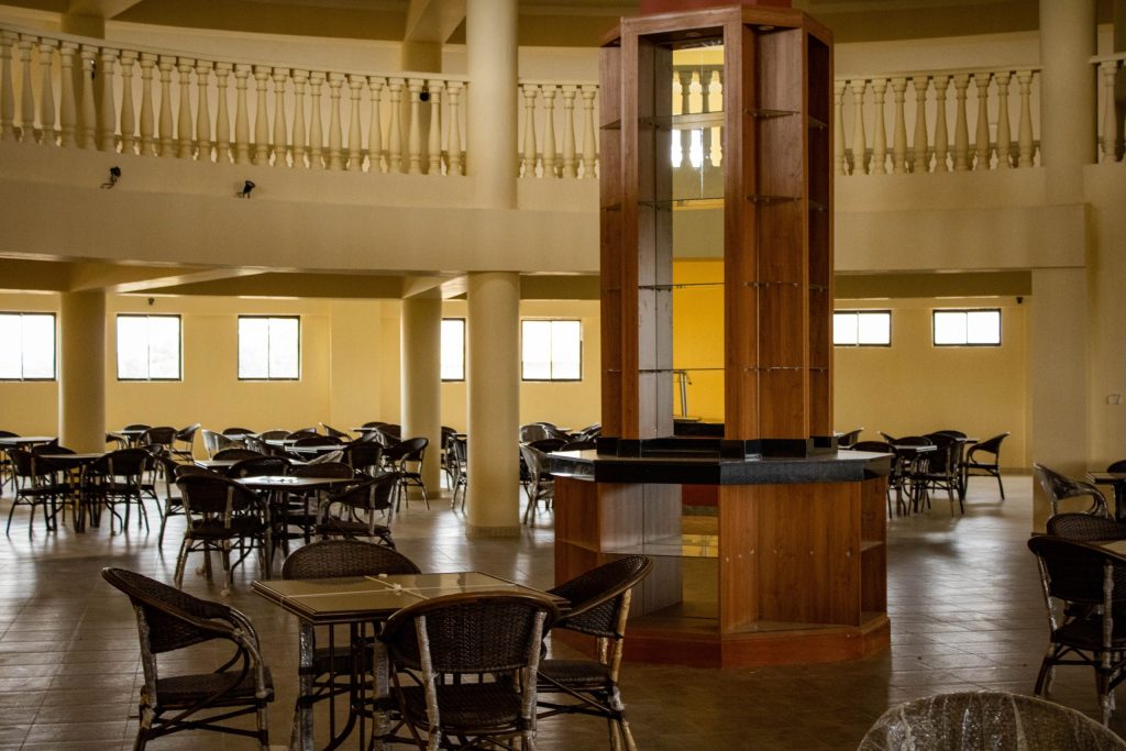 Spacious interior of Asili restaurant featuring elegant wooden display columns, woven dining chairs, and a grand mezzanine balcony.