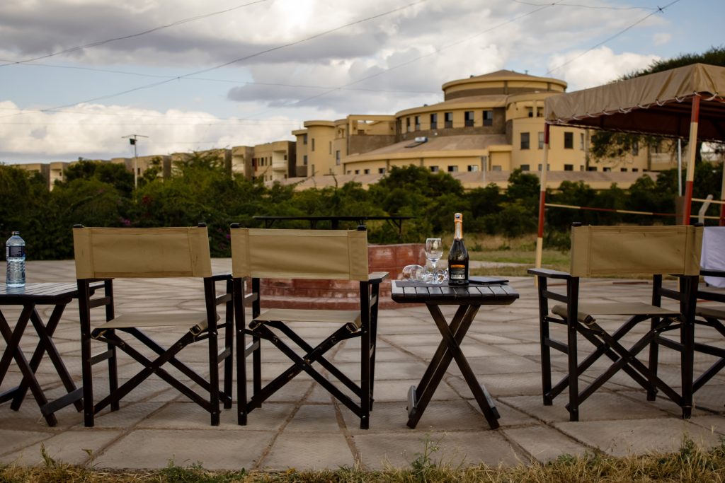 Outdoor lounge seating area around the Enkima Firepit with safari director chairs, side tables, and champagne set against the resort backdrop.