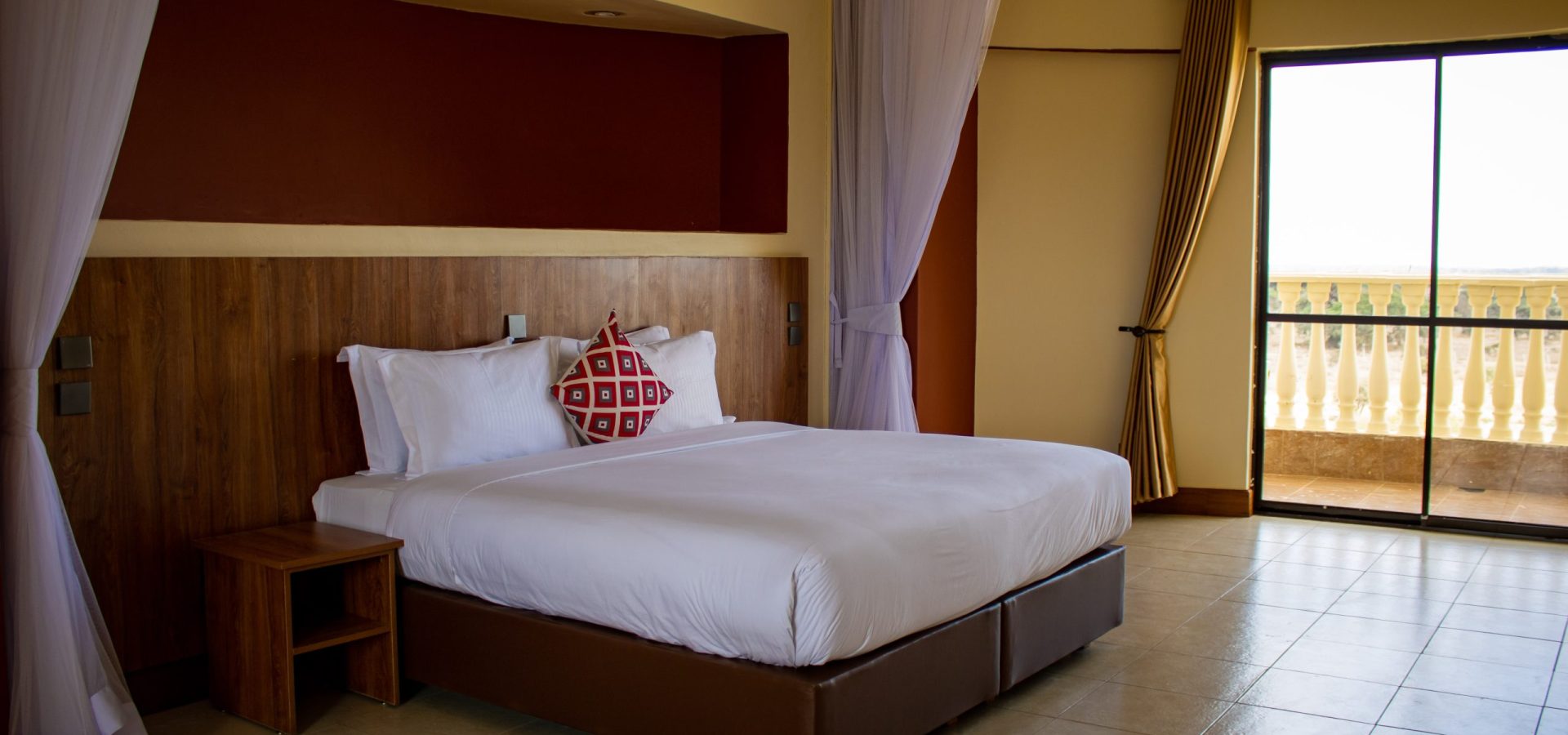 Spacious bedroom with a king bed, wooden headboard, and sliding glass doors leading to a private balcony.
