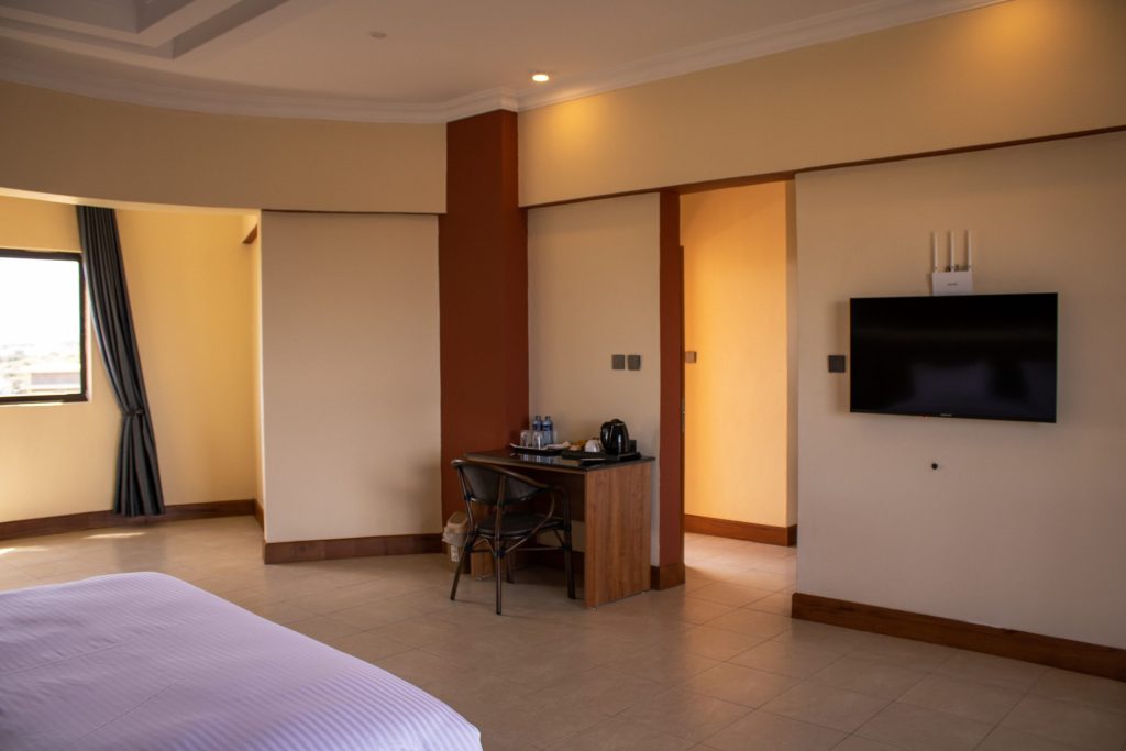 Interior view of an Executive Terrace Room showing a cozy bed, work desk with refreshment station, and wall-mounted television.