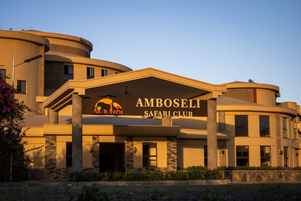 Grand main entrance and exterior facade of Amboseli Safari Club illuminated by warm evening sunlight.