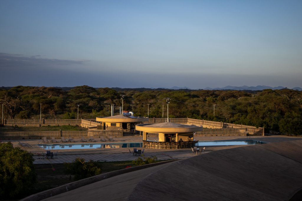 Panoramic view of Olkeju Pool Bar, surrounded by sun loungers, overlooking Kimana Sanctuary, the Chyulu Hills and the Amboseli savannah.
