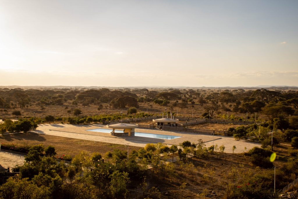 Elevated wide view of Olkeju Pool Bar and outdoor swimming pool deck overlooking the vast Amboseli savannah.