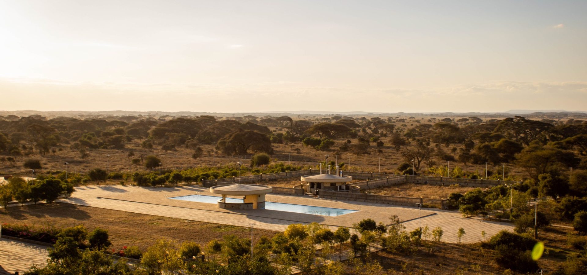 Elevated wide view of Olkeju Pool Bar and outdoor swimming pool deck overlooking the vast Amboseli savannah.