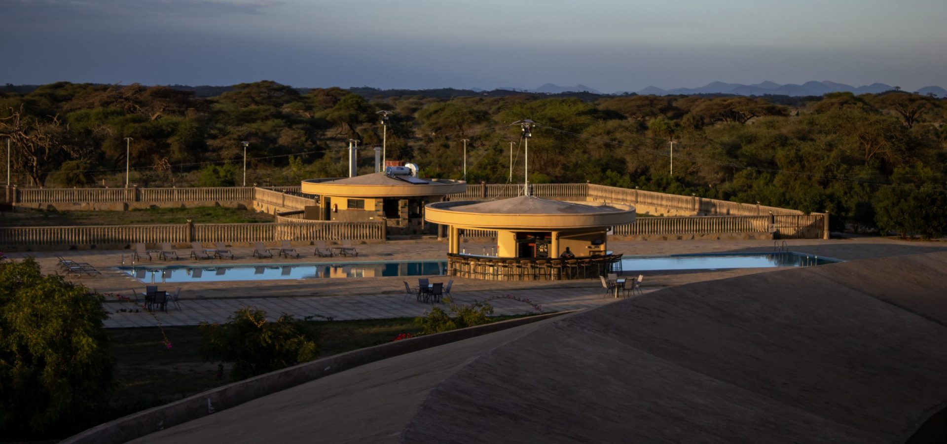 Panoramic view of Olkeju Pool Bar, surrounded by sun loungers, overlooking Kimana Sanctuary, the Chyulu Hills and the Amboseli savannah.