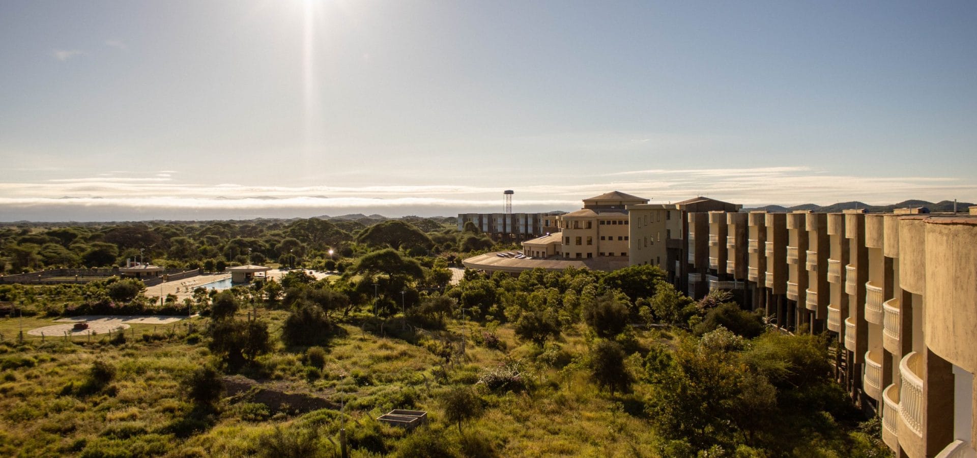 Elevated view of Amboseli Safari Club overlooking lush savannah under bright sun.